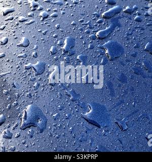 Wasser tropft auf eine Autohaube. Stockfoto