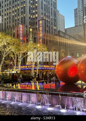 Während der Weihnachtszeit stapeln sich riesige Weihnachtsbaumornamente, die einen reflektierenden Pool gegenüber der Radio City Music Hall, 2021, New York City, USA, reflektieren Stockfoto