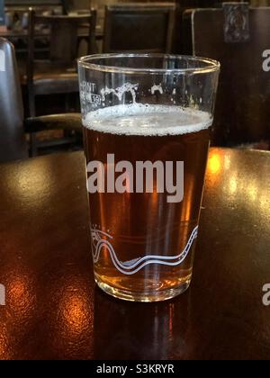 Ein teilbetrunkenes Pint bitterem Bier auf einem Pub-Tisch in London Stockfoto