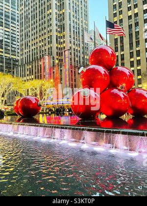 In der Weihnachtszeit, 2021, New York City, USA, stapeln sich riesige Weihnachtsbaumornamente in einem reflektierenden Pool gegenüber der Radio City Music Hall Stockfoto