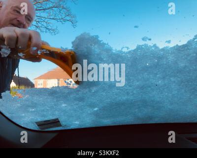 Mann, der Schnee von einer Autoscheibe entfernt Stockfoto