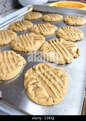 Hausgemachte Erdnussbutter-Kekse, die auf einer viel benutzten Backform aus dem Ofen heiss werden. Stockfoto