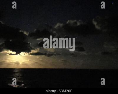 Vollmond hinter Wolken über dem Meer Stockfoto