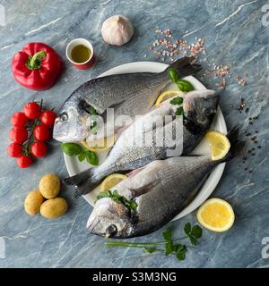 Frische Seebrasse mit Kartoffeln, roten Paprika und Kirschtomaten Stockfoto