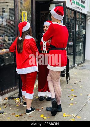 Drei Personen, die in Weihnachtsmann-Outfits gekleidet sind, genießen die SantaCon New York City am 2021. Dezember Stockfoto