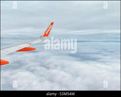 Ein Blick aus einem easyJet-Flugzeugfenster. Das Flugzeug fliegt über den Wolken in einem Winterhimmel. Viel Platz zum Kopieren. Keine Personen auf diesem Bild! Foto ©️ COLIN HOSKINS. Stockfoto