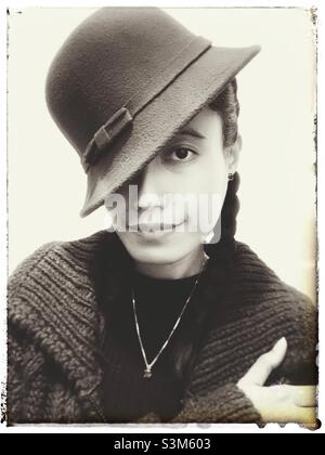 Das Porträt einer Frau, das ihr ein Auge mit dem Hut bedeckt. Schwarz und Weiß mit Vintage-Effekten. Stockfoto