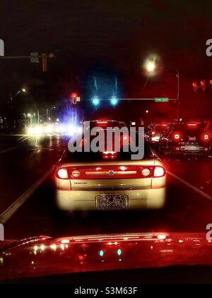 Stecken Sie im nächtlichen Verkehr an einer Kreuzung in Utah, USA, fest. Es ist klar, wie „Nachtblindheit“ für manche Menschen ein Problem sein könnte, mit all den verschiedenen und kontrastierenden Lichtern, Reflexionen und Blendungen. Stockfoto