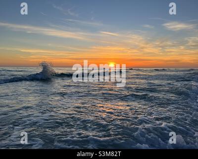 Wellengang mit goldenem Sonnenuntergang Himmel Hintergrund Stockfoto