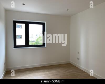 Leeres Schlafzimmer mit einem quadratischen Fenster und weißen Wänden Stockfoto
