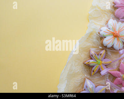 Draufsicht flach lag auf gelbem Hintergrund von hausgemachten handgemachten Lebkuchen in Form von Blumen mit bunten Glasur bedeckt, Kopierraum. Stockfoto