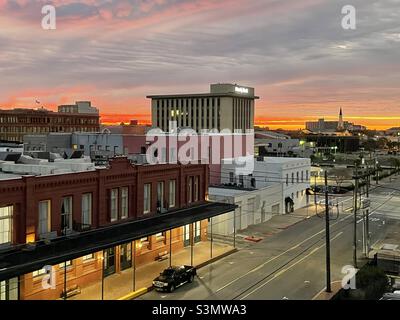 Sonnenaufgang in der Innenstadt von Galveston, mit Blick auf den Golf von Mexiko, 1/4/2022. Diese Ansicht stammt von der Mechanic Street und zeigt Markt- und Poststraßen sowie lokale Unternehmen. Stockfoto