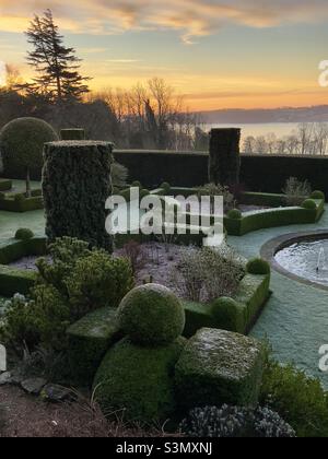 Das Parterre eines Landhaushotels, im Winter, mit formalem topiary bedeckt mit Frost im frühen Morgenlicht Stockfoto