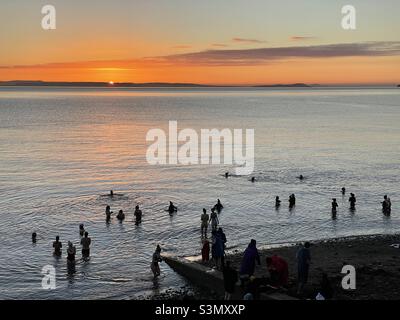 Kaltwasserschwimmer bei Sonnenaufgang an der Küste von Penarth, South Wales, Mitte Januar. Stockfoto