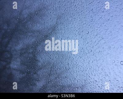 Regen fällt auf das Fenster mit Schnee draußen Stockfoto