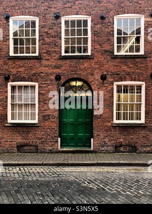 Ein großartiges altes Stadthaus mit großer grüner Tür und Schiebefenstern auf einer gepflasterten Straße in einer historischen britischen Stadt Stockfoto