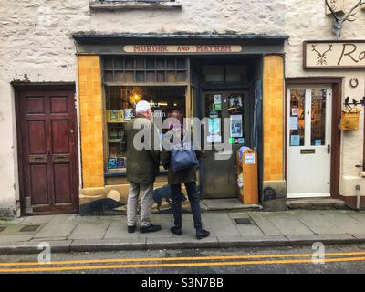Hay on Wye Wales UK – Besucher stöbern in der Schaufensteransicht des auf Kriminalbücher spezialisierten Buchhändlers The Murder und Mayhem Stockfoto