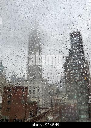 Das Empire State Building ist in Nebel gehüllt, als es durch ein regnerisches Fenster in New York City gesehen wird Stockfoto