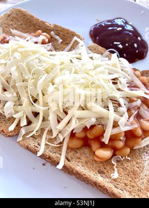 Bohnen auf Toast mit geriebenem Cheddar-Käse und brauner Sauce Stockfoto