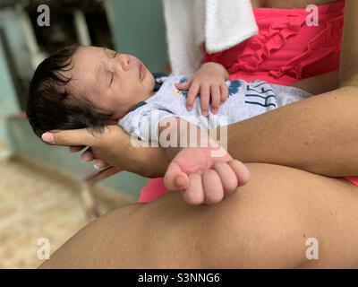 Neugeborenes Baby schläft‘den Armen seiner Mutter. Zwei Wochen alter Junge. Mutterschaft Stockfoto