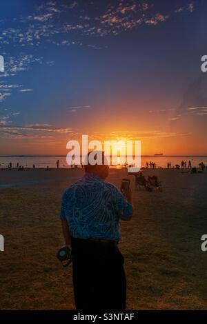 Atemberaubende Sonnenuntergang Silhouette Hintergrund mit einem Menschen Vordergrund beobachten Sonnenuntergang und viele Menschen Hintergrund Ala Moana Beach Park in Honolulu Stadt Oahu Insel Hawaii Stockfoto