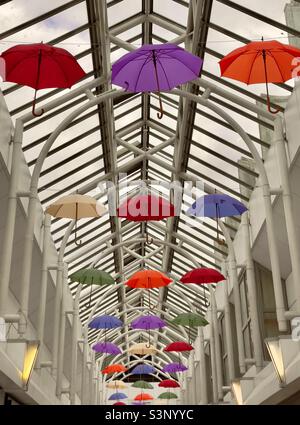 Eine dekorative Ausstellung von farbigen Regenschirmen, die an den Oberlichtern im Crown Gate Shopping Center in Worcester, Großbritannien, hängen Stockfoto