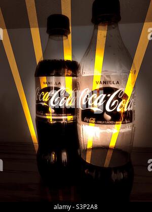 Zwei Flaschen Vanilla Coke, eine voll und die andere fast leer. Digitale Änderungen, wie Grunge-Effekt und gelbe Lichtstrahlen, über verschiedene IOS-Apps durchgeführt. Stockfoto