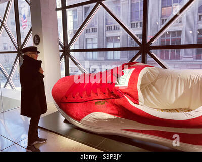 Puma Store Ausstellung eines riesigen Schuhs mit einem Kunden im Flagship Store auf der Fifth Avenue, 2022, New York City, USA Stockfoto