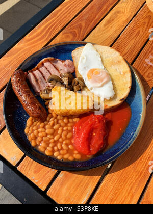 Englisches Frühstück mit Spiegelei, Speck. Bohnen, Champignons, Hash Brown, Wurst und Tomaten Stockfoto