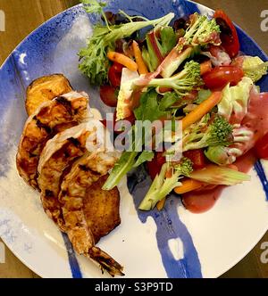 Nahaufnahme eines Tellers mit gegrillten Garnelen über gegrilltem Lachs mit Gemüse und Salat. Stockfoto
