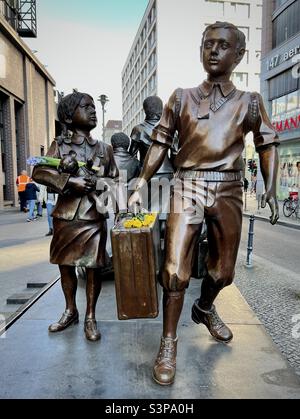 Deutschland, Berlin. 27. März 2022. Gelbe und blaue Blumen erinnern an die Notlage ukrainischer Kinder während der russischen Militärinvasion. (Skulptur - Kindertransport von Frank Meisler) Stockfoto