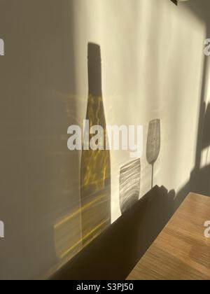 Schatten an einer Wand. Leere Weinflasche, 2 Gläser. Stockfoto