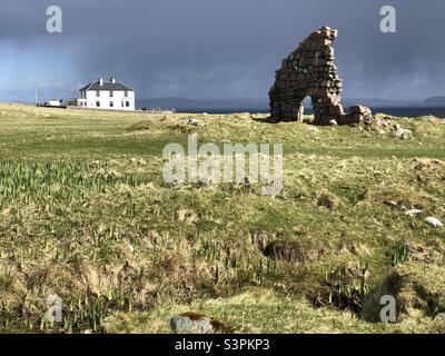 Weißes Haus und Ruine unter einem brütenden Himmel, Isle of Iona, Schottland Stockfoto