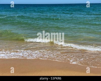 Meereswelle an einem sonnigen Sandstrand in Portugal. Stockfoto