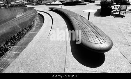 LOS ANGELES, CA, 2021. MÄRZ: Gebogene Holzbank neben dem Brunnen am City National Plaza, Downtown Financial District. Schwarz und Weiß Stockfoto