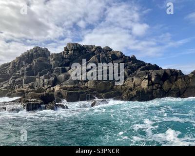 Ein wildes Meer, das sich gegen eine felsige Insel, Isles of Scilly, wascht Stockfoto