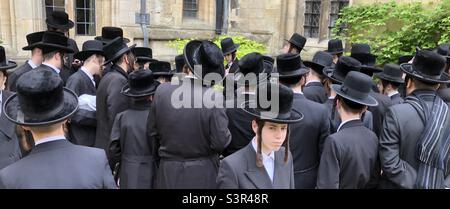 Eine Gruppe ultraorthodoxer Juden, die im Freien neben einem Denkmal an einer mittelalterlichen Grabstätte in Oxford beten. Stockfoto