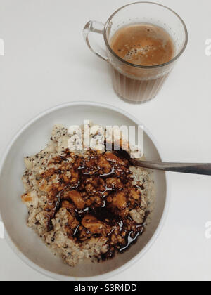 Hafermehl Porridge serviert mit Kaffee, der auch mit Hafermilch veganes Frühstück serviert wird Stockfoto