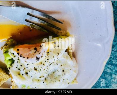 Gebratene Eier auf Toast auf einem weißen Teller mit einer Gabel öffnen Stockfoto