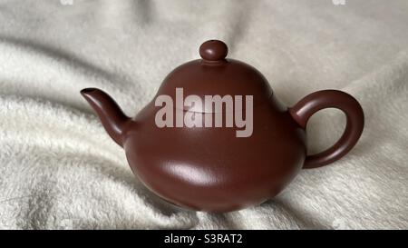 Eine handgefertigte Yixing Zisha Teekanne mit glattem, abgerundetem Design, die die traditionelle Handwerkskunst und Einfachheit der chinesischen Teekultur unterstreicht. Stockfoto