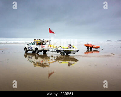 RNLI-Rettungsschwimmer mit roter Flagge am Perranporth Beach, Cornwall, Großbritannien, an einem stürmischen Tag. Stockfoto