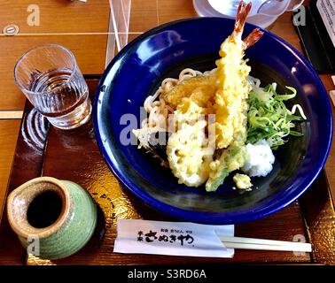 Japanische udon-Nudeln mit Shrimp Tempura und Gemüse auf einer blauen Schüssel, traditionelles japanisches Mittagessen Stockfoto