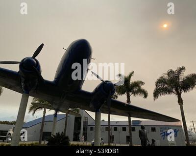LOS ANGELES, CA, SEP 2021: Douglas DC3 Monument mit Palmen vor dem Museum of Flying am Santa Monica Municipal Airport, verschwommener Nachmittag mit niedriger, schwacher Sonne Stockfoto