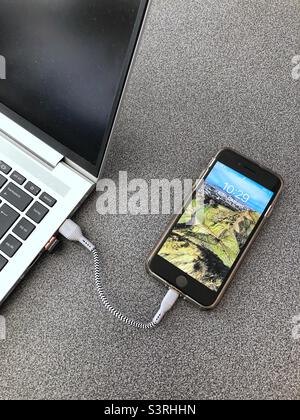 Apple iPhone SE Mobile Smartphone aufladen über USB-Anschluss des Laptops Stockfoto