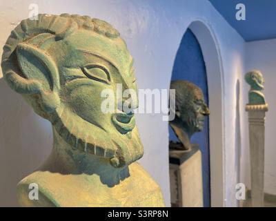 Zwei Büsten von Faunen im griechischen Stil flankieren eine Nische mit einer Porträtbüste von Sir Clough Williams Ellis in Portmeirion, Nordwales Stockfoto