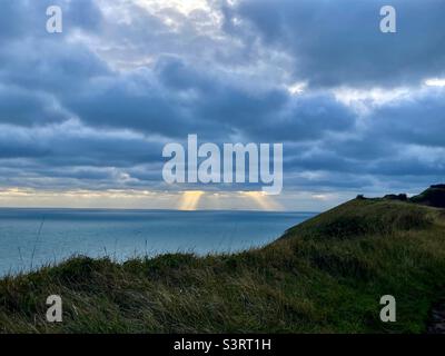 Sonnenstrahlen kommen durch die Wolken über dem Meer Stockfoto