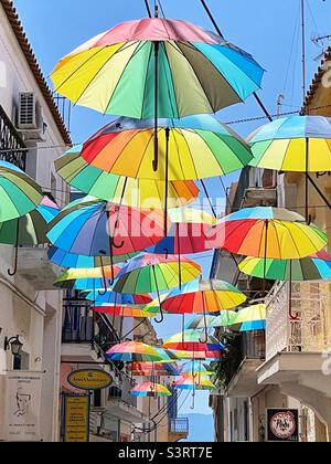 Farbige Regenschirme, die über einer schmalen Straße auf der Insel Aegina in Griechenland hängen Stockfoto