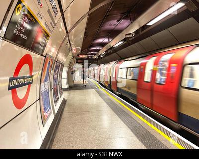 Bahnsteig an der U-Bahn-Station London Bridge, von der aus eine U-Bahn fährt. Langsame Verschlusszeit zur Verwacklung von Bewegungen. Stockfoto