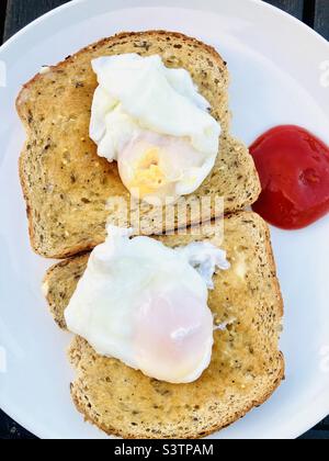 Pochierte Eier werden auf einem Vollkorntoast mit Tomatensauce serviert Stockfoto