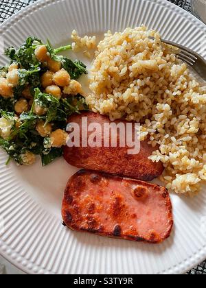 Nahaufnahme einer Mahlzeit mit gebratenem Spam, braunem Reis und einem Garbanzo-Bohnensalat, 2022, USA Stockfoto